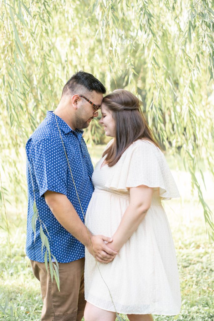 couple snuggles close under a willow tree at airfield falls