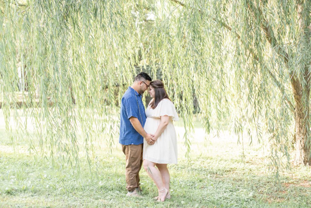 expecting couple snuggles close under a willow tree at airfield falls in fort worth