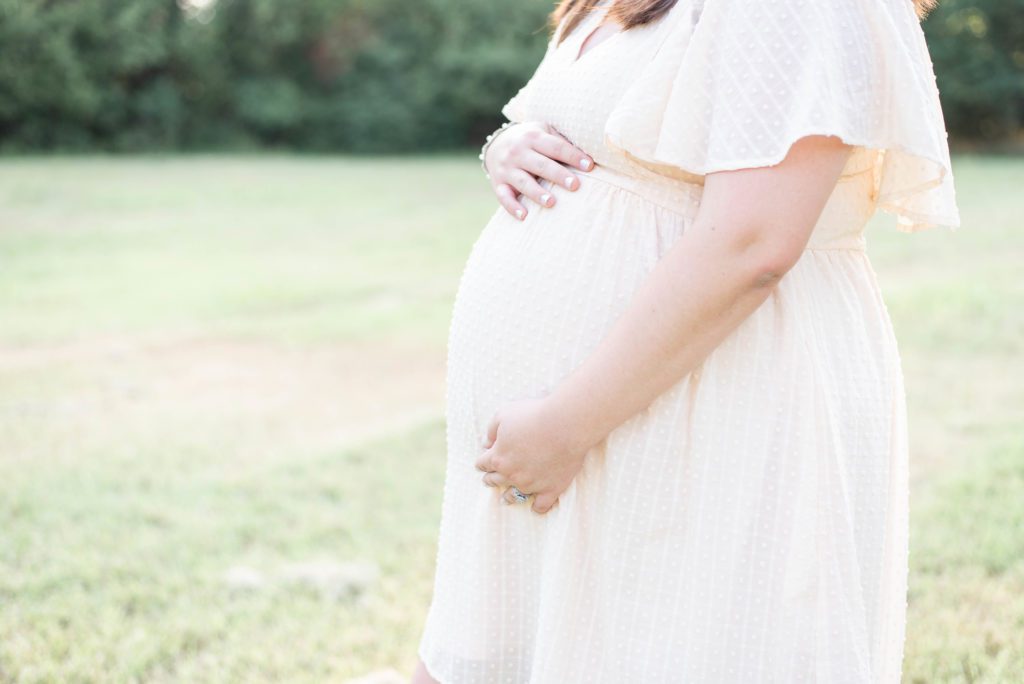 close up of a pregnant woman's belly wearing a cream colored dress